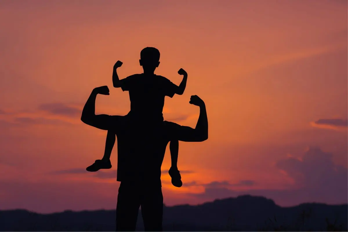 Silhouette eines Vaters mit Kind auf den Schultern im Sonnenuntergang